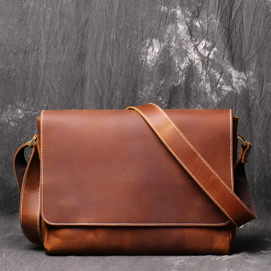 Vintage brown leather men's messenger bag with a cover flap, showing the internal document and phone pockets.