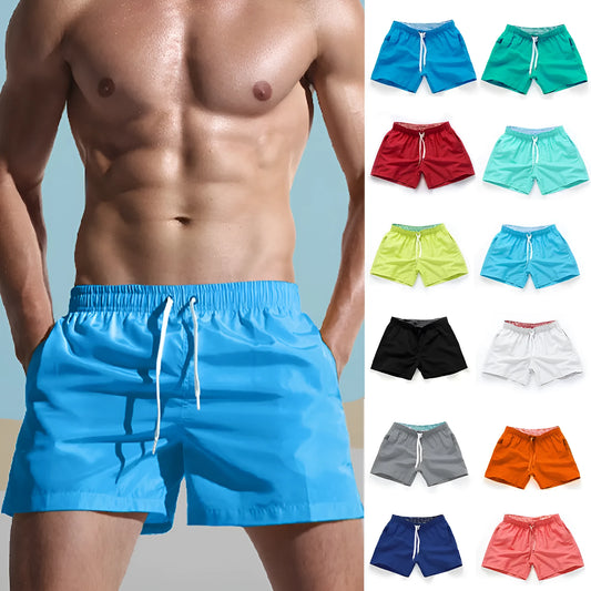 Man wearing straight-leg polyester beach shorts in a bright colour on the sand.
