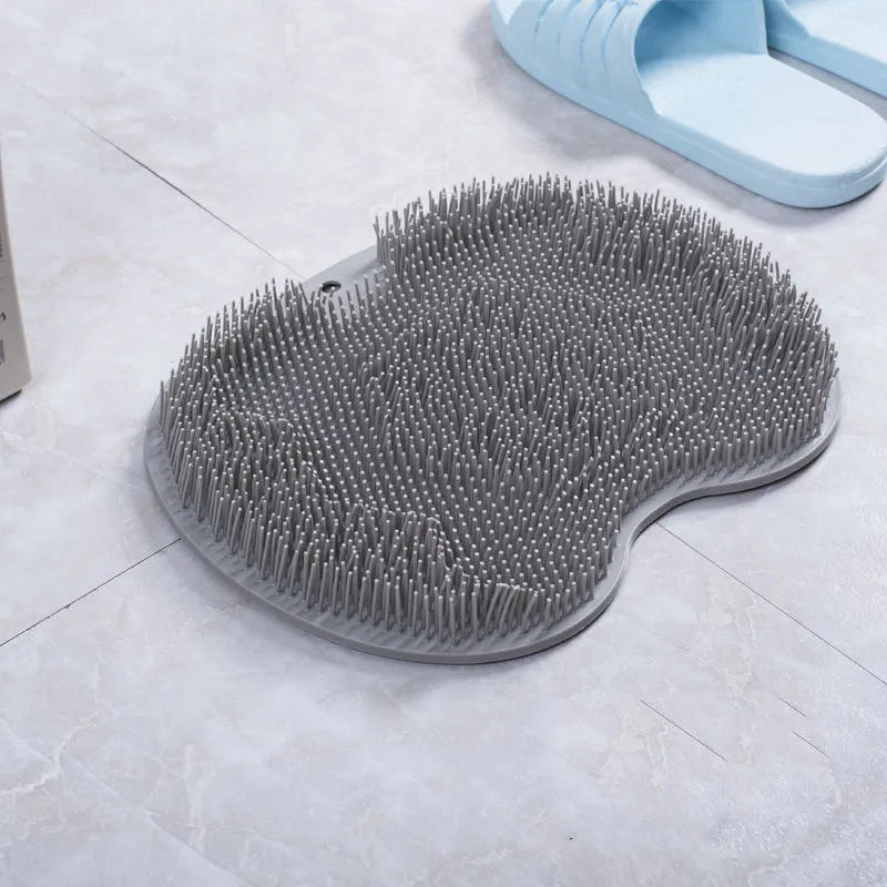 Orange non-slip massage bath brush with silicone bristles and suction cup base on shower floor