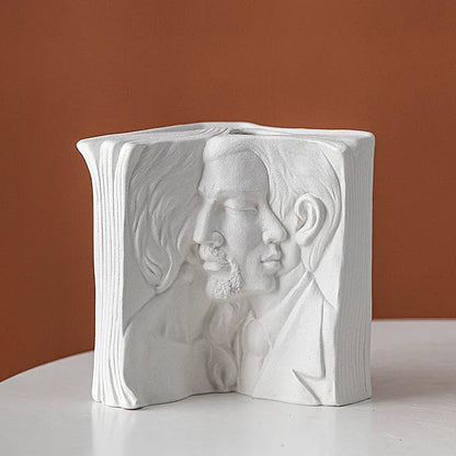 White ceramic book stand holding an open book at an angle, with a wire page holder in use.