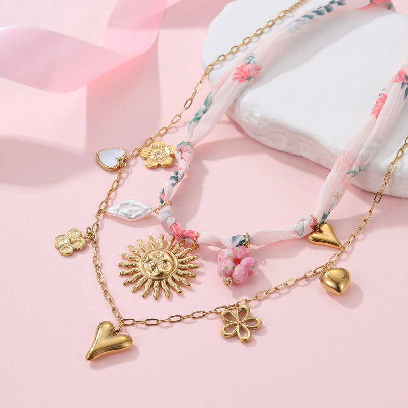 Women's stainless steel necklace with 18K gold electroplating, available in 41cm to 50cm chain length, featuring a geometric sun pendant design in heart or ribbon sun styles for fashion and everyday wear