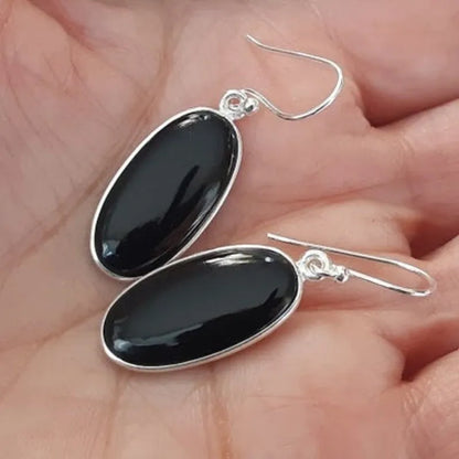 Women's geometric earrings with a black oval agate pendant in a silver electroplated frame.