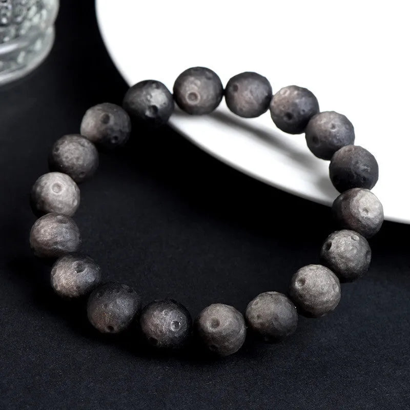 Natural obsidian crater ball bracelet with grinding treatment showing smooth bead texture in silver or golden meteorite colours