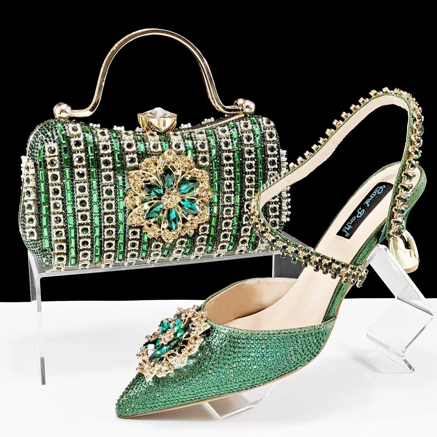 Women's black high-heel ankle strap shoes with floral rhinestone buckle and matching clutch bag on a neutral background