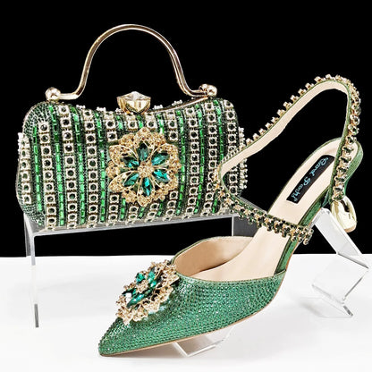 Women's black high-heel ankle strap shoes with floral rhinestone buckle and matching clutch bag on a neutral background