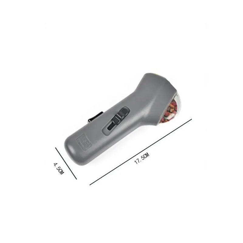 Grey plastic pet snack catapult launcher toy with ergonomic handle, shown with treats.
