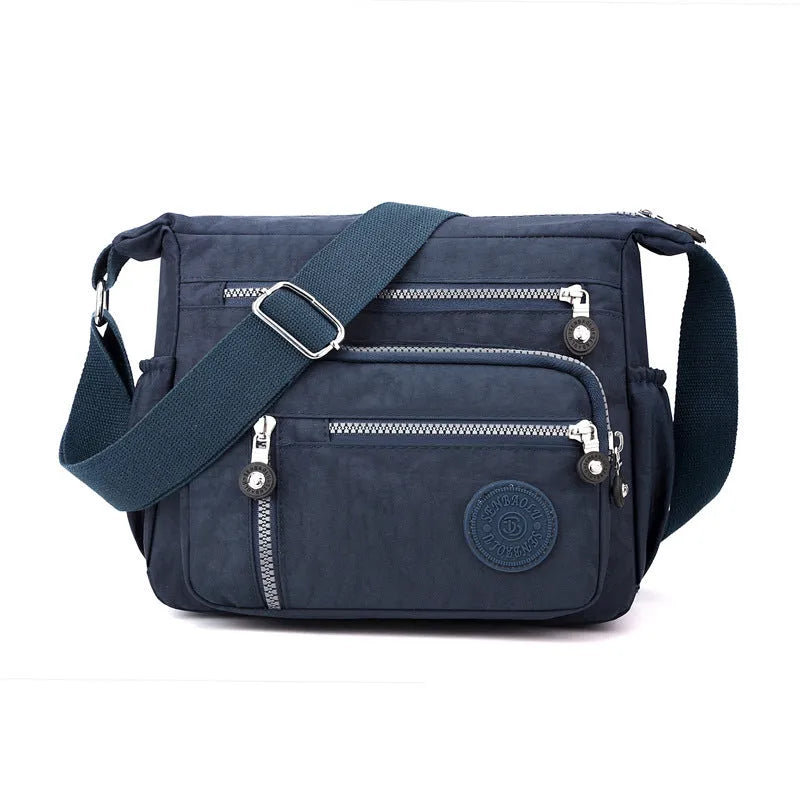 Soft grey nylon messenger bag with a single shoulder strap, shown in a square vertical shape.