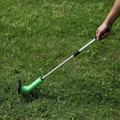Cordless handheld lawn trimmer with green housing, extension pole, debris shield, and pack of zip ties on a garden lawn.