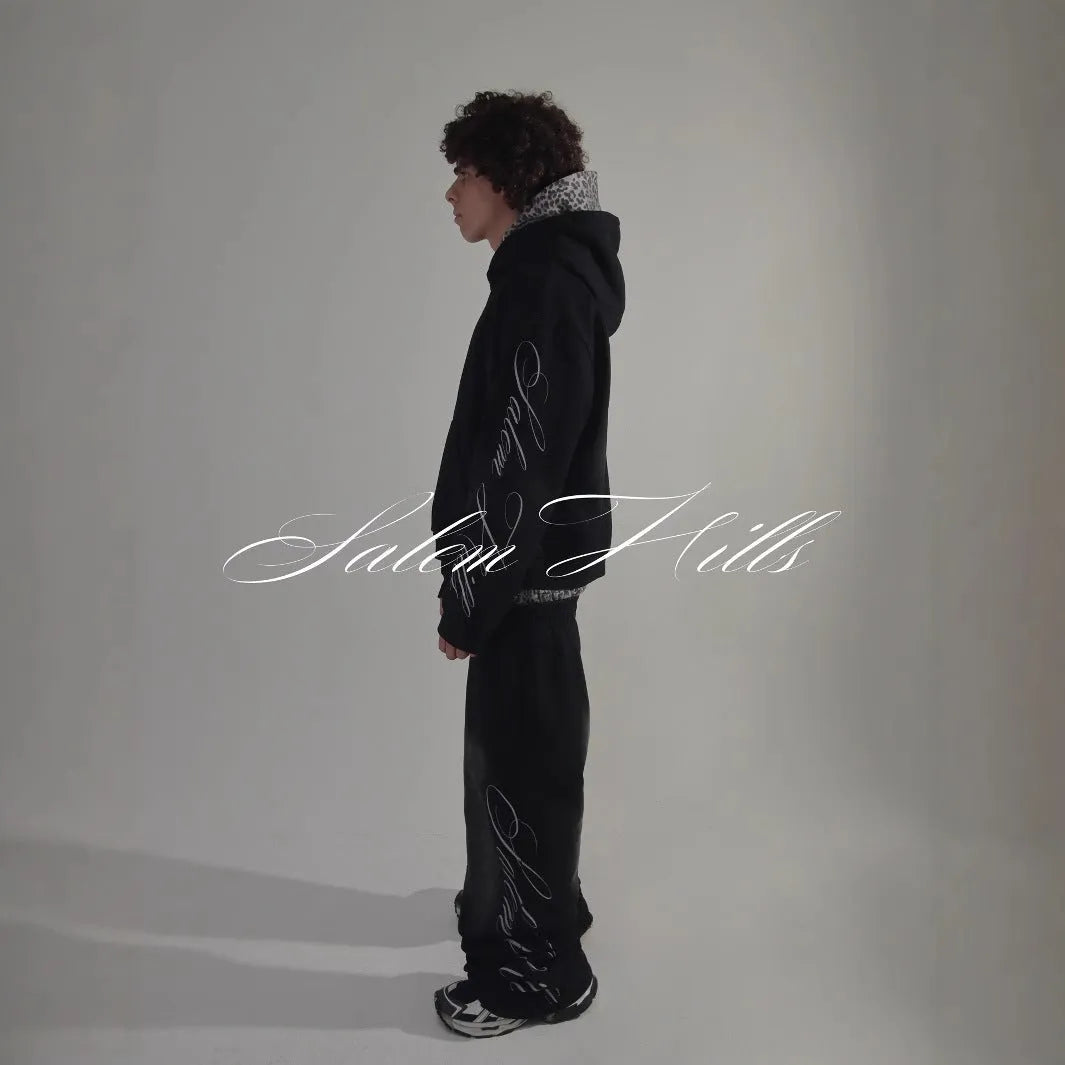 Man wearing a black punk print hoodie and matching trousers, a casual lounge suit set.