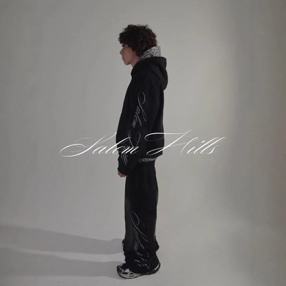 Man wearing a black punk print hoodie and matching trousers, a casual lounge suit set.