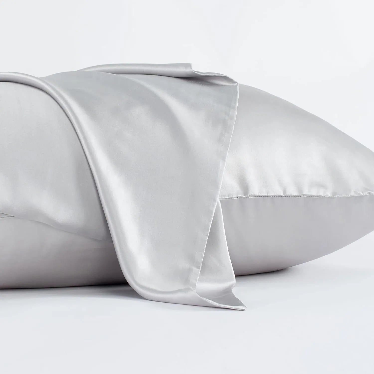 Dark grey silk pillowcase with envelope closure on a bed.