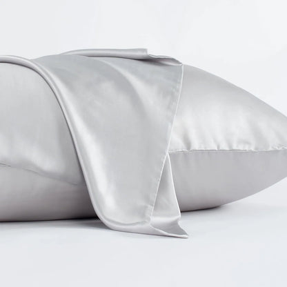 Dark grey silk pillowcase with envelope closure on a bed.