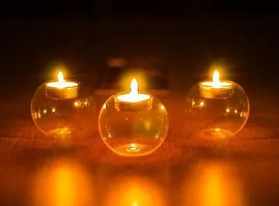Handmade round hollow glass candle holder in three sizes on a table.