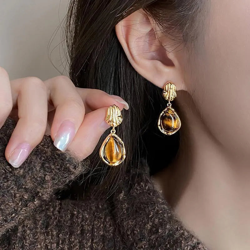 Three pairs of handmade alloy holiday earrings with geometric shapes and tassel details on display