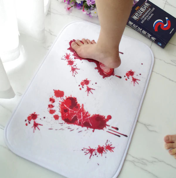 A rectangular bath mat with a vivid, lifelike blood-splatter design made of durable polyester material.