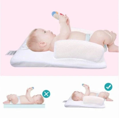 Newborn baby sleeping comfortably on the Baby Sleep Fixed Position & Anti Roll Pillow, with elevated head and air vent bumpers for optimal breathing and cooling.