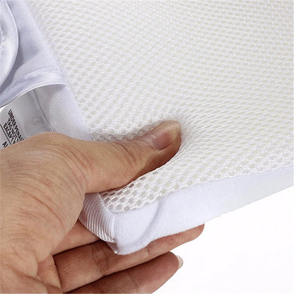 Newborn baby sleeping comfortably on the Baby Sleep Fixed Position & Anti Roll Pillow, with elevated head and air vent bumpers for optimal breathing and cooling.