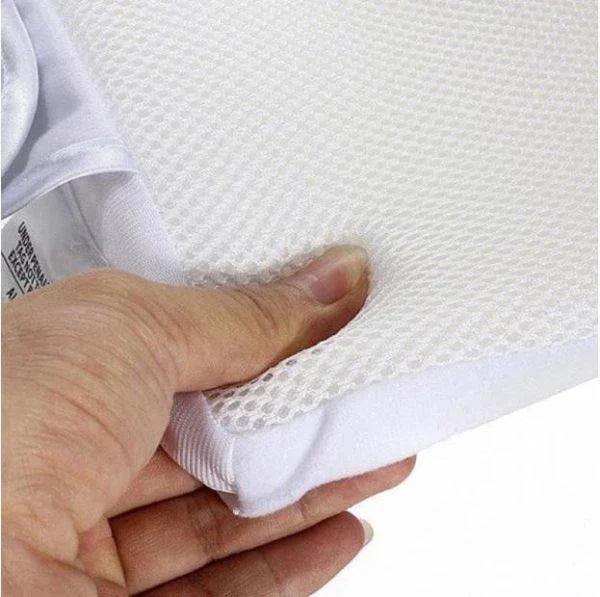 Newborn baby sleeping comfortably on the Baby Sleep Fixed Position & Anti Roll Pillow, with elevated head and air vent bumpers for optimal breathing and cooling.