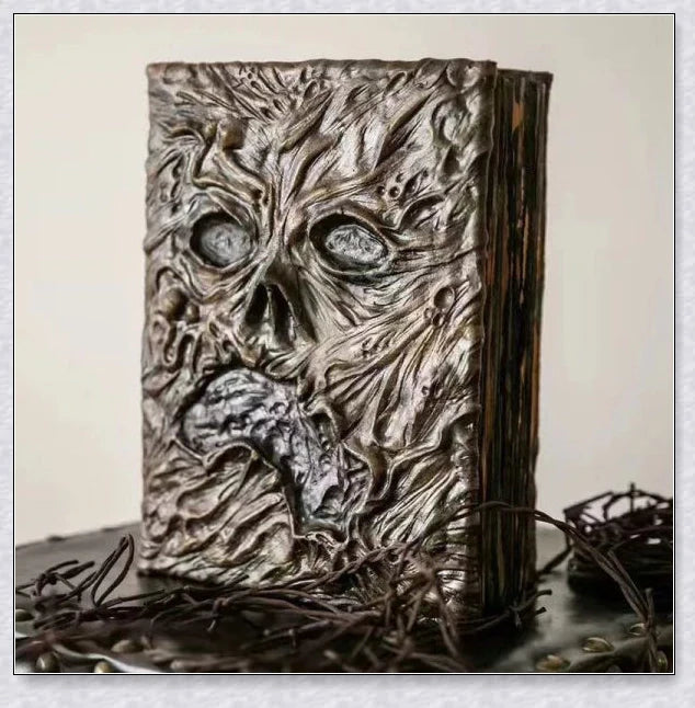 Necronomicon-inspired dark magic prop book with demonic face binding and barbed wire wrapping