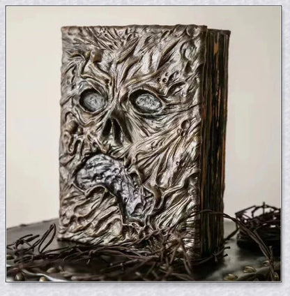 Necronomicon-inspired dark magic prop book with demonic face binding and barbed wire wrapping