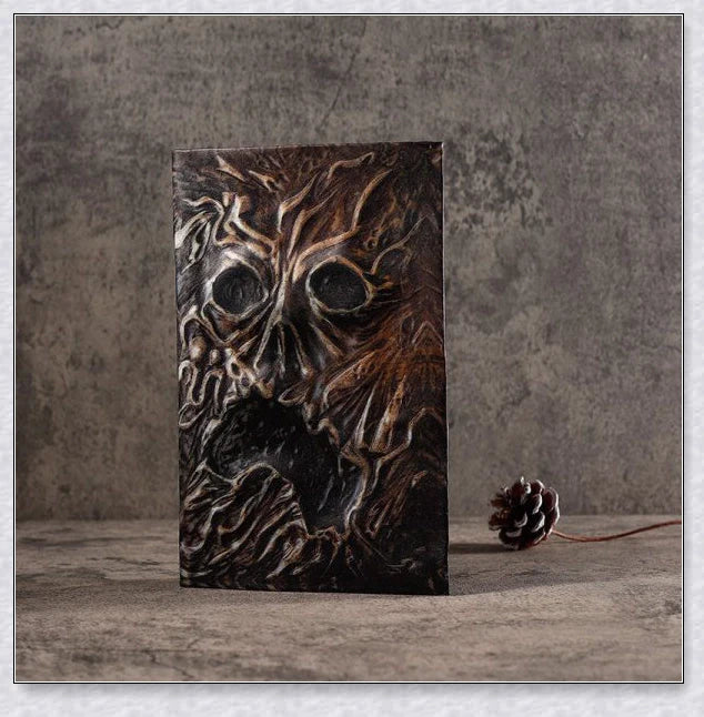 Necronomicon-inspired dark magic prop book with demonic face binding and barbed wire wrapping