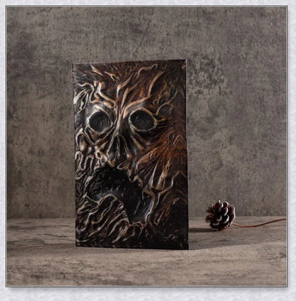 Necronomicon-inspired dark magic prop book with demonic face binding and barbed wire wrapping