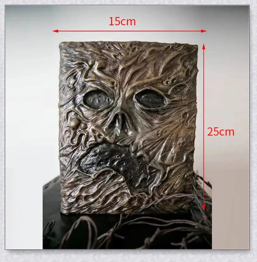 Necronomicon-inspired dark magic prop book with demonic face binding and barbed wire wrapping