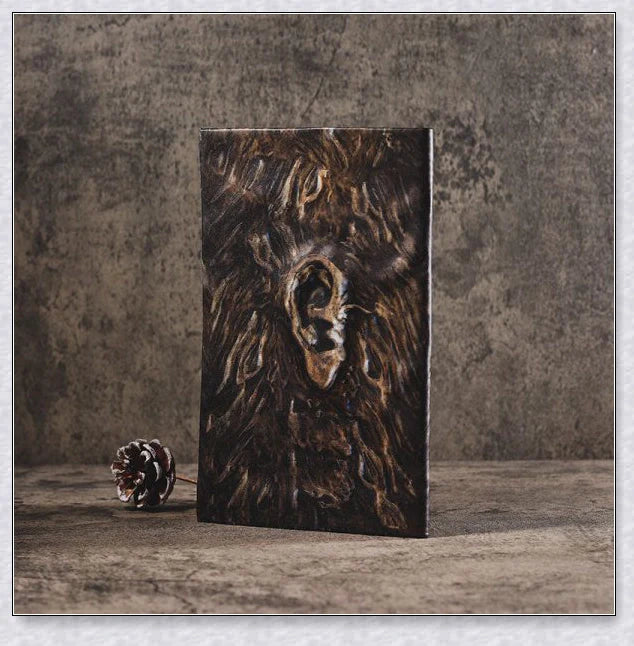 Necronomicon-inspired dark magic prop book with demonic face binding and barbed wire wrapping