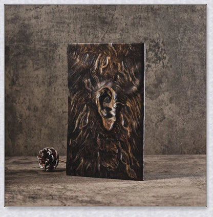 Necronomicon-inspired dark magic prop book with demonic face binding and barbed wire wrapping