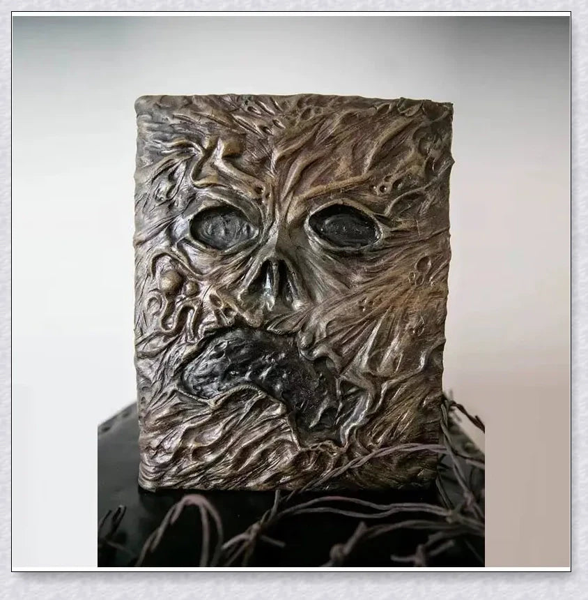 Necronomicon-inspired dark magic prop book with demonic face binding and barbed wire wrapping