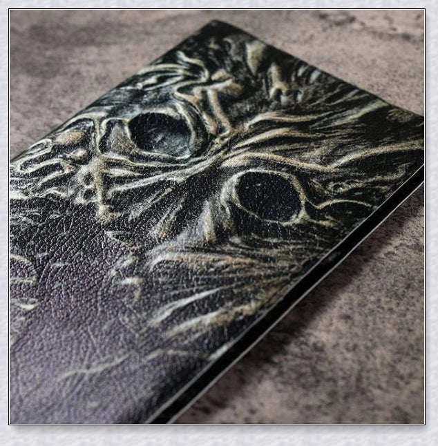 Necronomicon-inspired dark magic prop book with demonic face binding and barbed wire wrapping