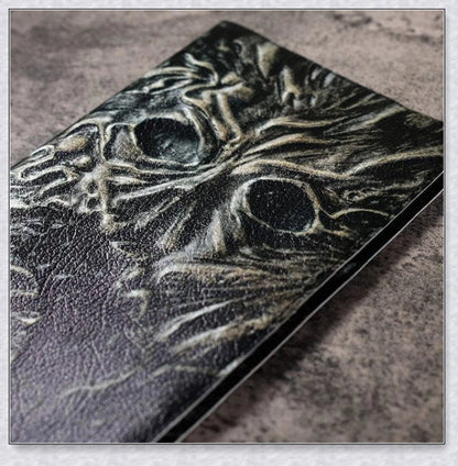 Necronomicon-inspired dark magic prop book with demonic face binding and barbed wire wrapping