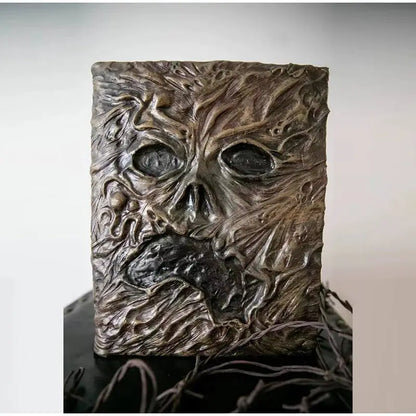 Necronomicon-inspired dark magic prop book with demonic face binding and barbed wire wrapping