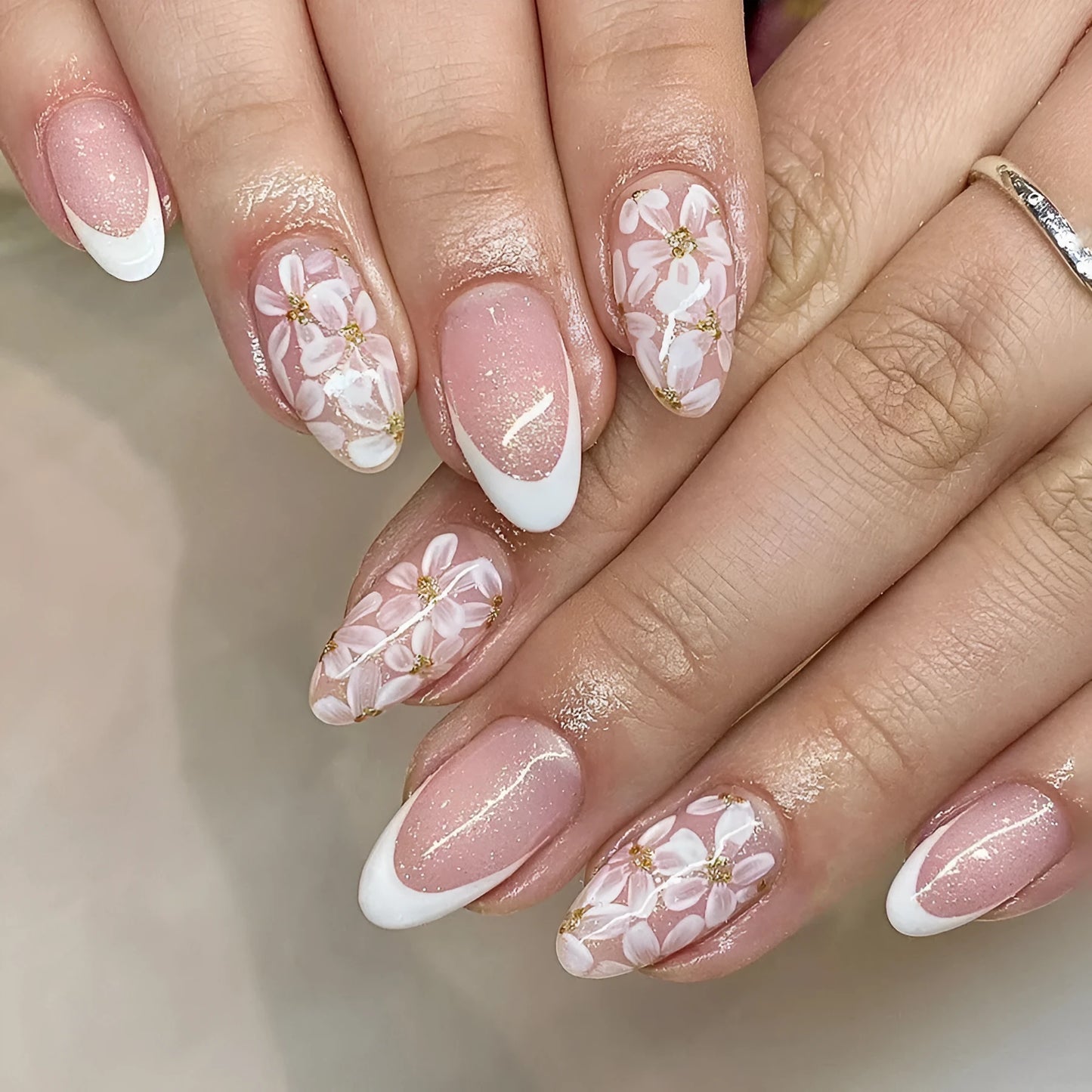 Short glossy almond artificial French nails with glitter flower design on white tips