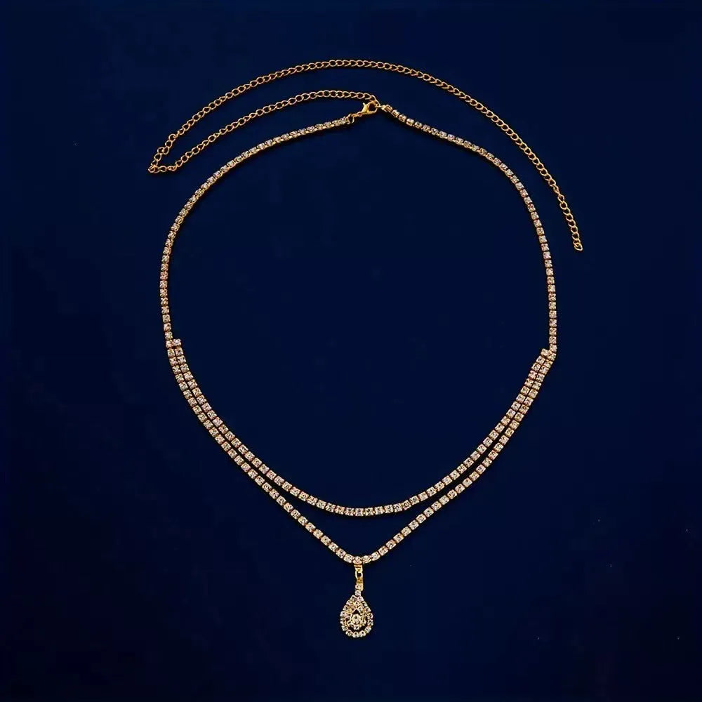Gold water drop pendant waist chain with tassel detail and lobster buckle closure on white background