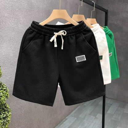 Man's solid colour casual sports shorts in micro-elastic polyester fabric on a beach background
