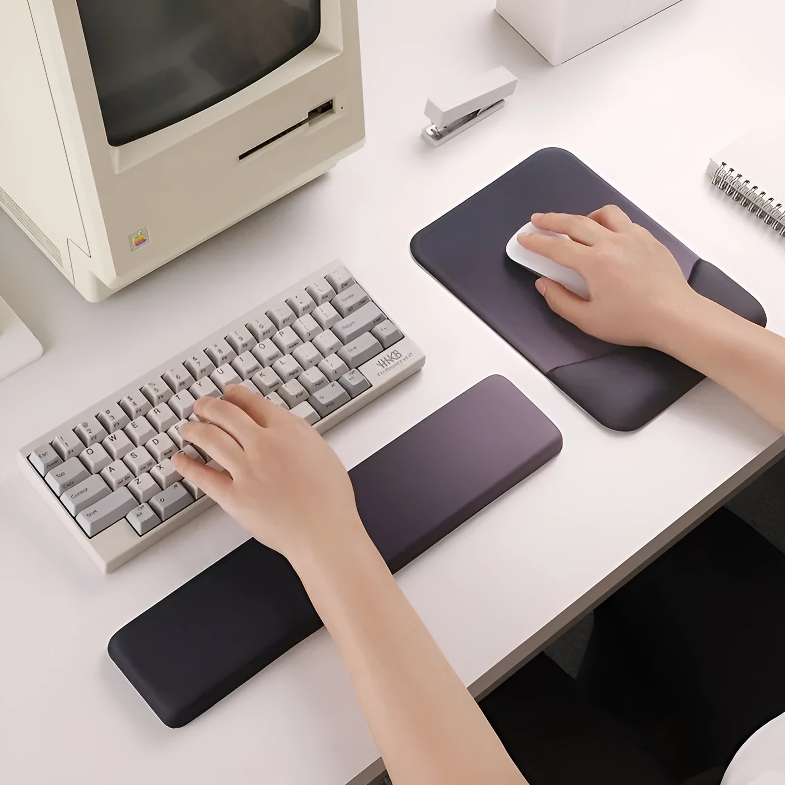Square cloth mouse pad with grey silicone gel wrist rest and hand pillow on a wooden desk.