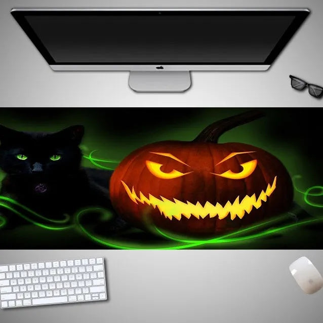 Oversized black mouse pad with Halloween-themed graphic, shown on a wooden desk with keyboard and gaming mouse.