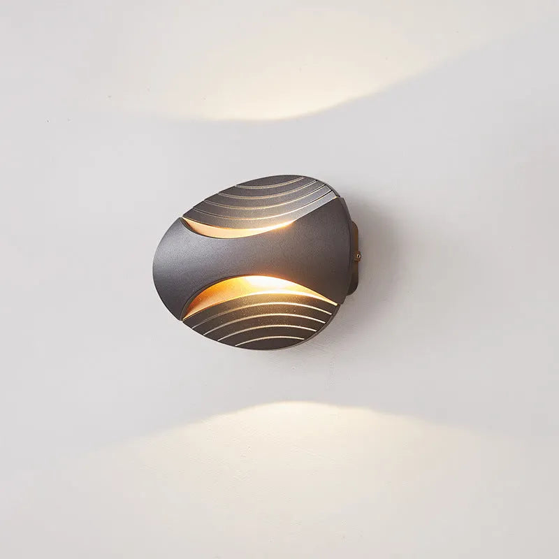 Modern aluminium wall lamp in black finish mounted beside a bed, emitting warm LED light.