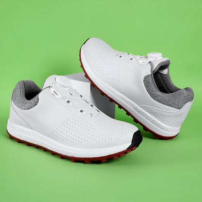 Men's white and black casual golf shoes with perforated upper and low-top design on a grass surface.