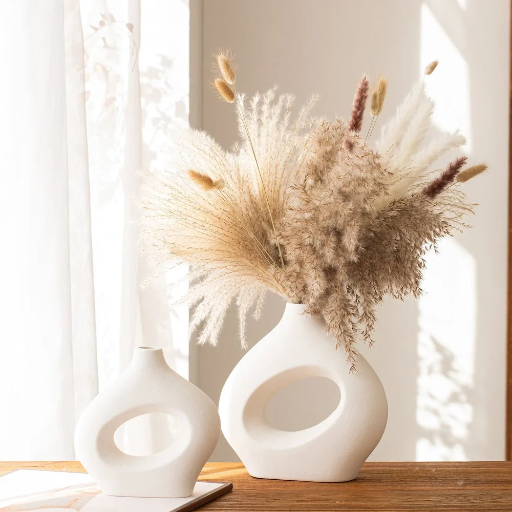 White ceramic circle vase with hand-painted coloured glaze on wooden table with dried flowers