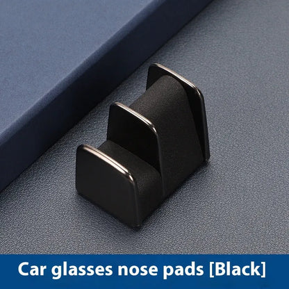 Green zinc alloy and leather glasses clip holder attached to a car dashboard, holding sunglasses.