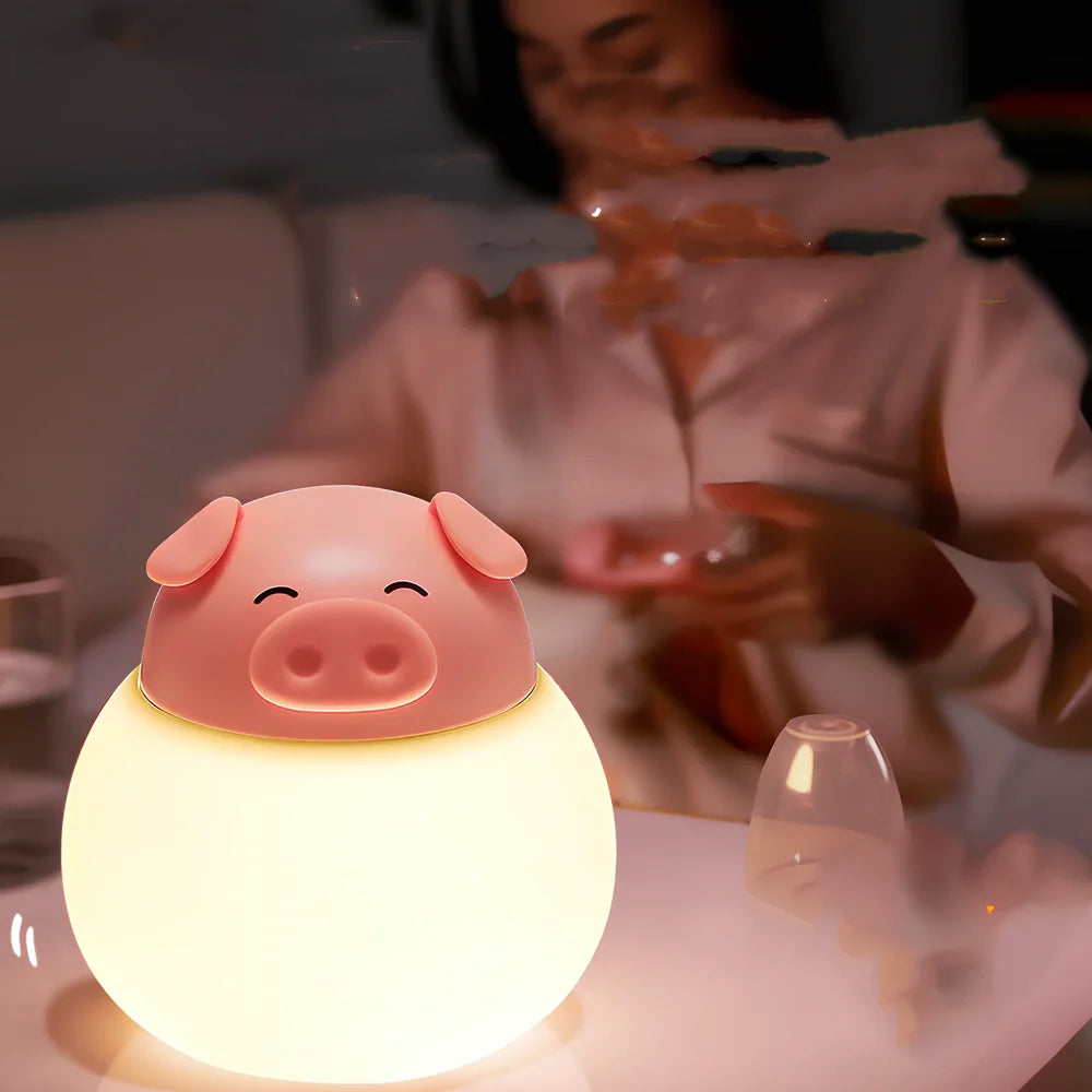 Pink silicone pig-shaped bedside lamp with adjustable lighting on wooden table