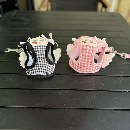 Small dog wearing adjustable cotton harness in pink with chest-back design and hand holding rope attachment