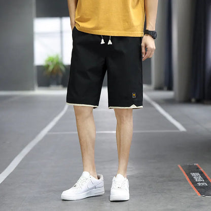 Man wearing loose straight-leg beach shorts in khaki, showcasing the South Korean style fit and micro-elastic waistband.