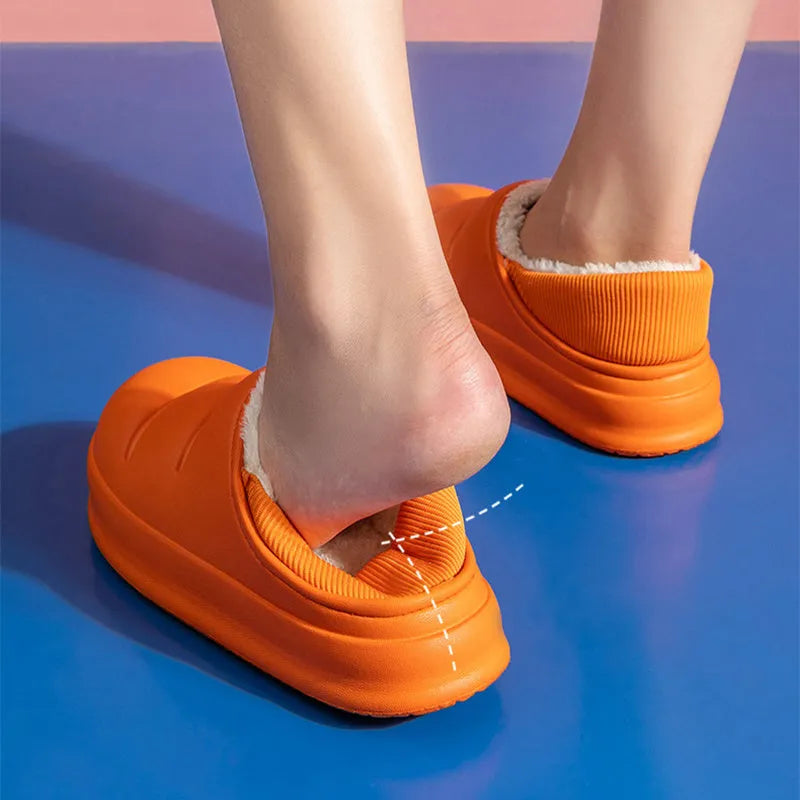 A pair of yellow EVA sleeve-style slippers with a plush lining and a textured non-slip sole, on a wooden floor.