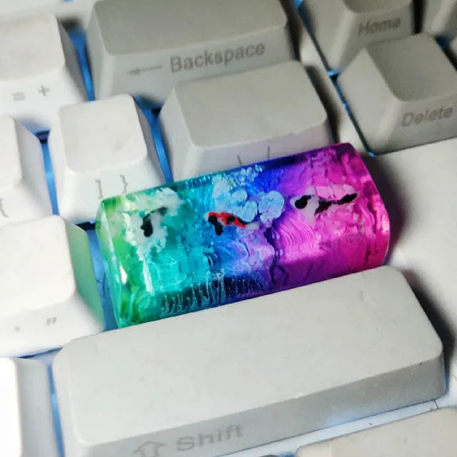 Close-up of a custom resin keycap featuring a detailed blue and orange koi fish scene, designed for Cherry MX mechanical keyboards.