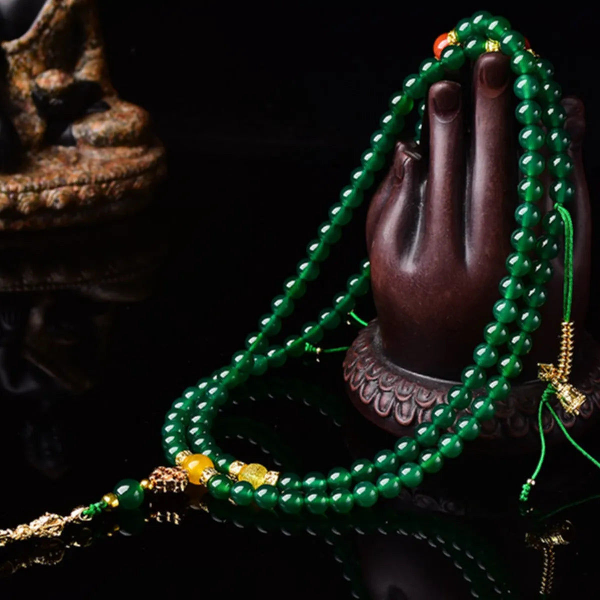 Close-up of a multi-strand green agate bracelet with natural stones on a wrist.