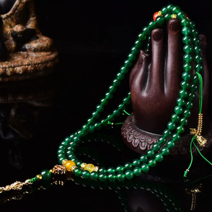 Close-up of a multi-strand green agate bracelet with natural stones on a wrist.
