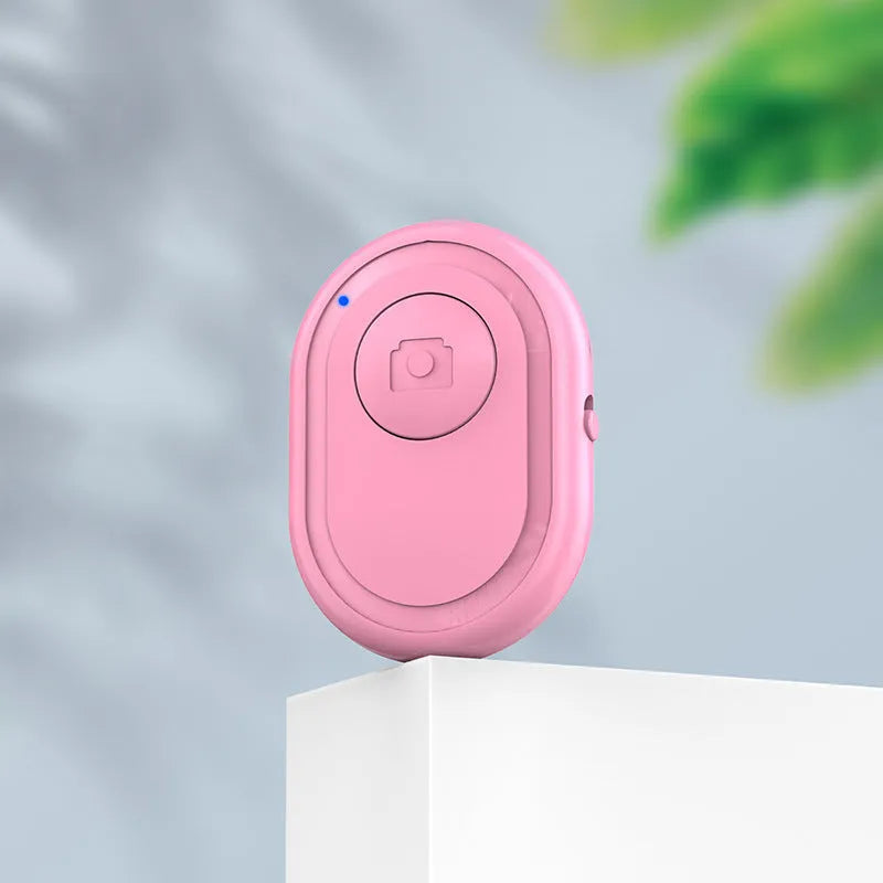 Small black wireless Bluetooth remote control for smartphone camera with self-timer function.